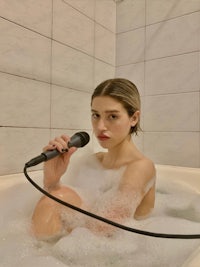 a woman is sitting in a bathtub with a microphone