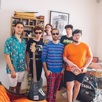 a group of people standing in a living room with a guitar